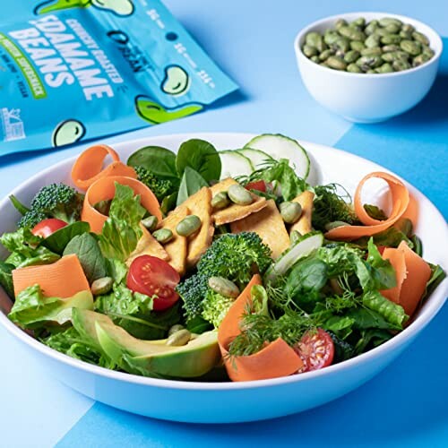 Colorful salad with vegetables, chips, and edamame on a blue background.